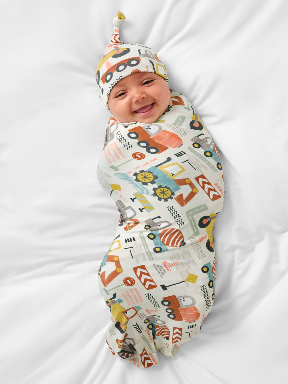 Aerial view of baby wearing the Mini Builders Swaddle & Hat Set