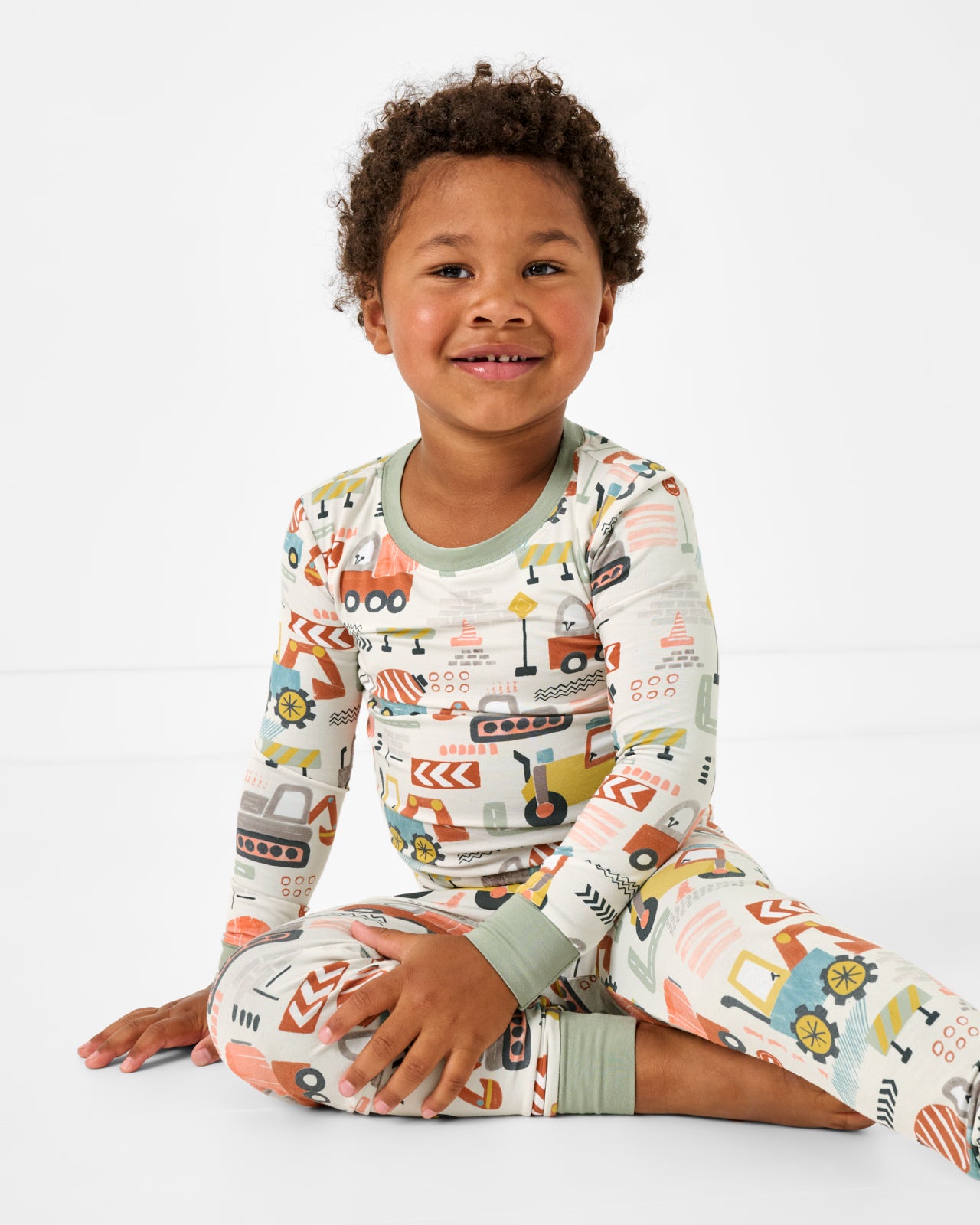 Sitting boy wearing the Mini Builders Two-Piece Pajama Set
