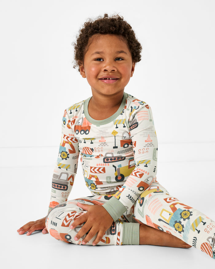 Sitting boy wearing the Mini Builders Two-Piece Pajama Set