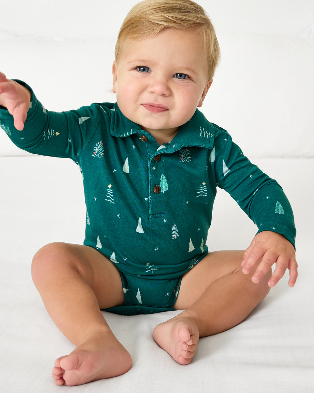 Sitting baby wearing the Twinkling Trees Polo Bodysuit