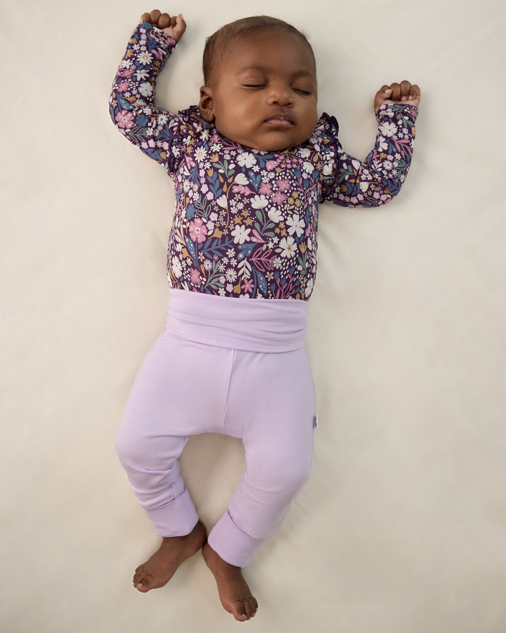 Aerial view of newborn wearing the Misty Lavender Fold Over Legging and Midnight Petals girls bodysuit