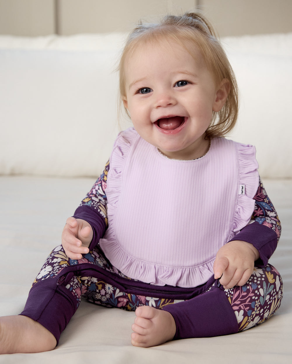 Sitting newborn wearing the Misty Lavender Ribbed Ruffle Bib