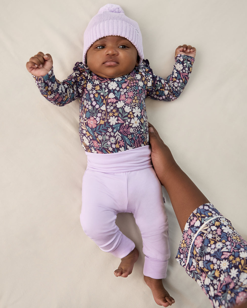Newborn baby wearing the Misty Lavender Fold Over Legging with a matching beanie and floral bodysuit