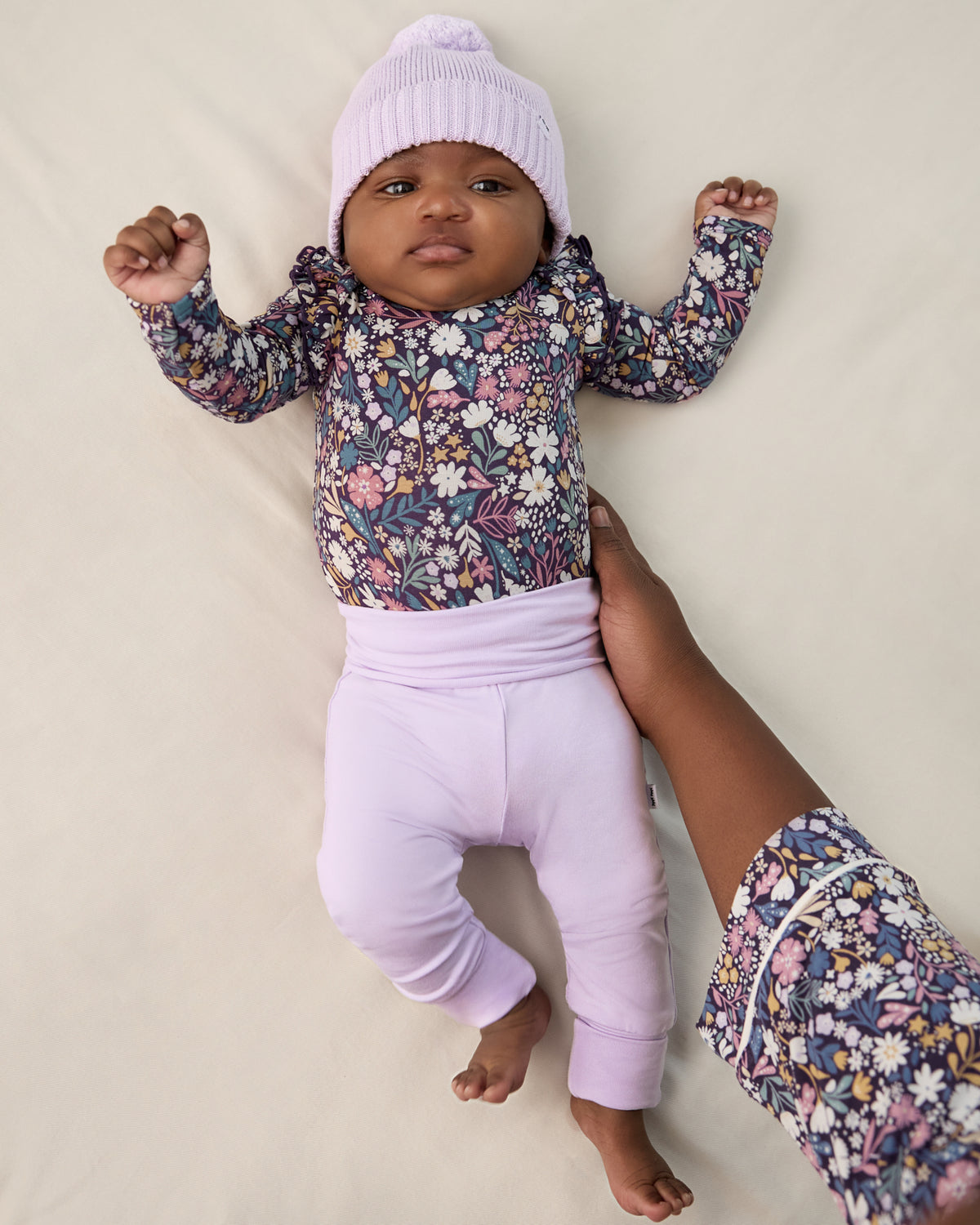Newborn baby wearing the Misty Lavender Fold Over Legging with a matching beanie and floral bodysuit