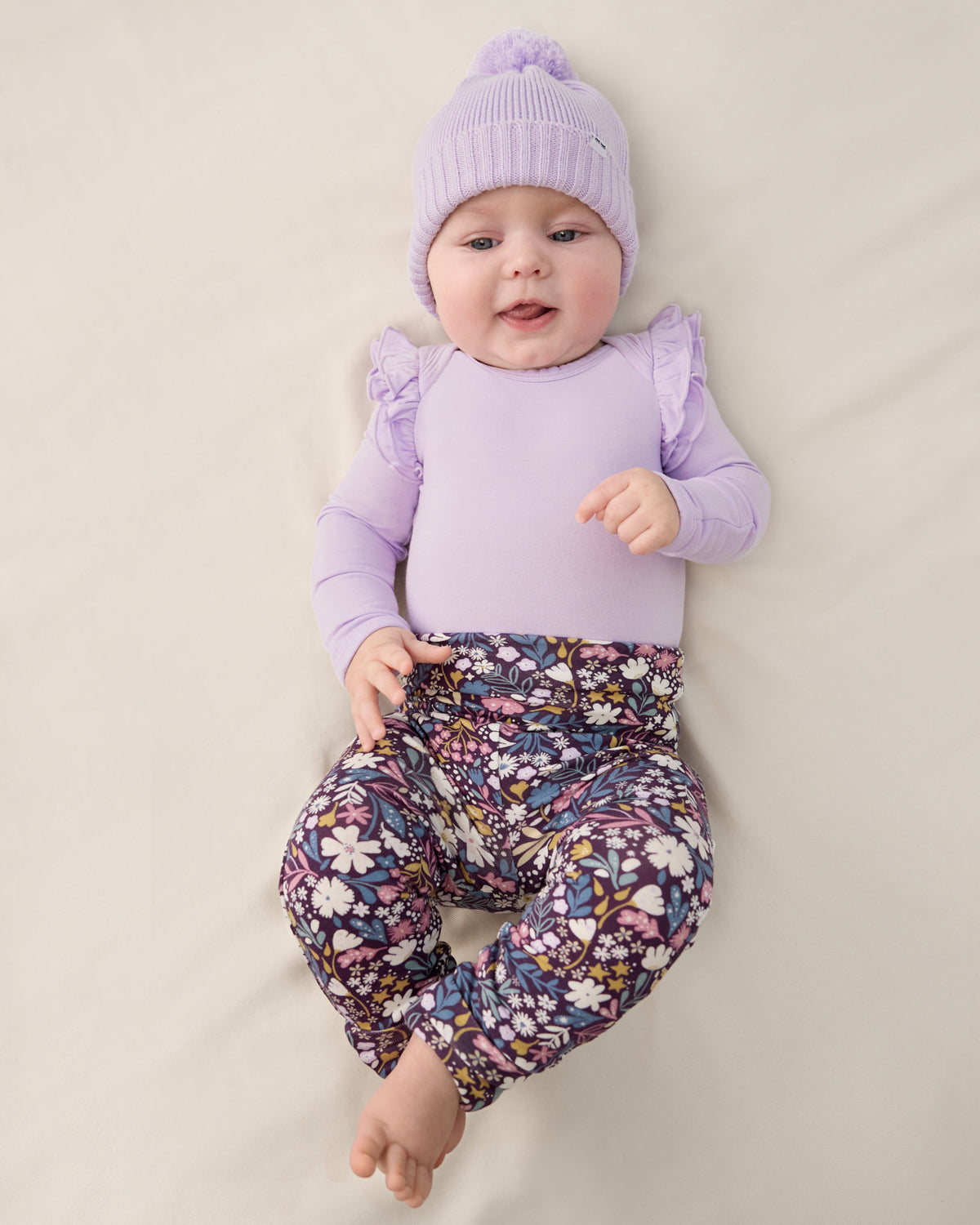 Newborn wearing the Midnight Petals Fold Over Legging with a purple beanie and bodysuit