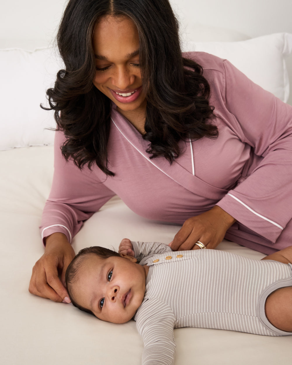 Woman wearing the Rosewood Women's Robe on a white bed