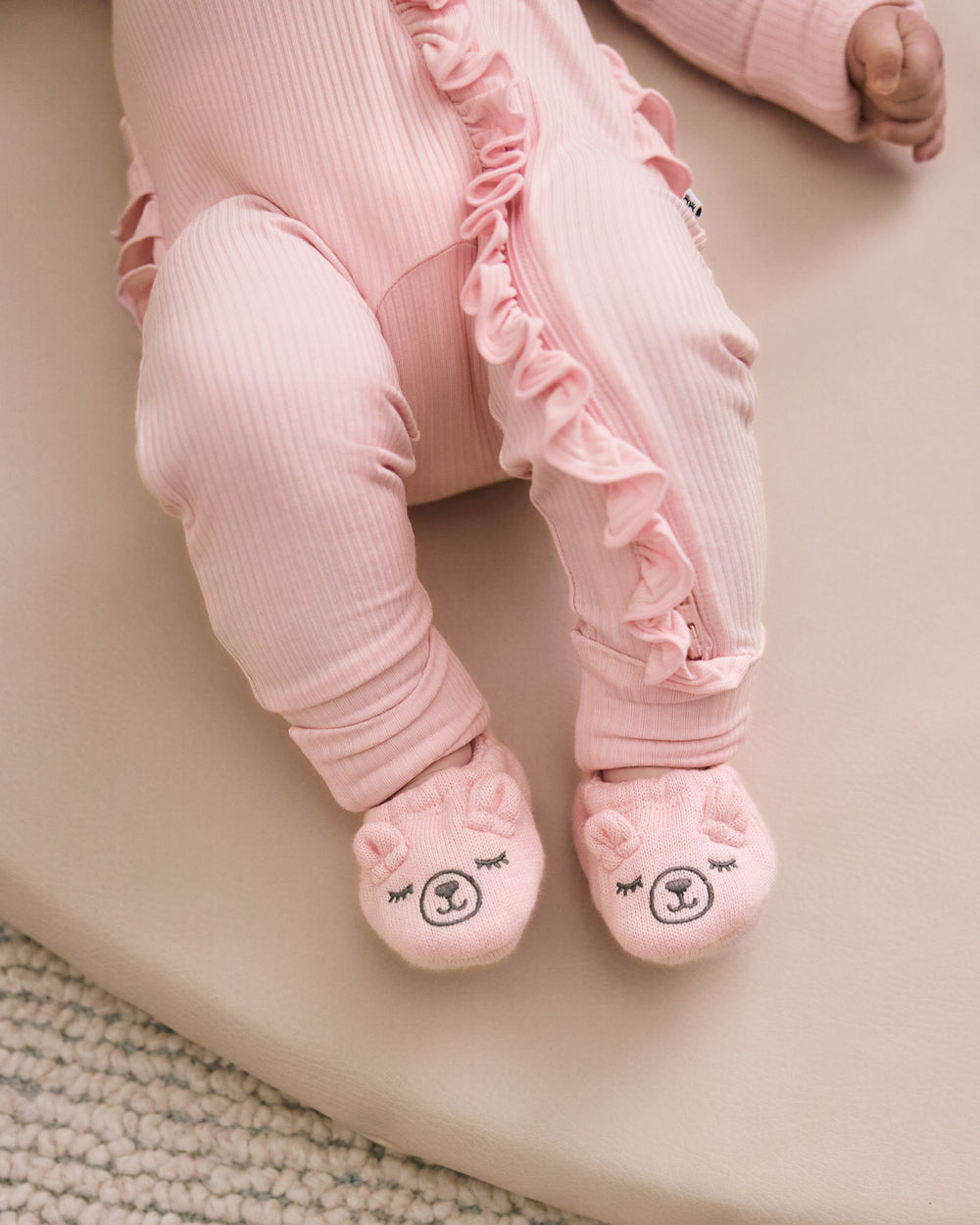 Baby wearing the Prima Pink Bear Booties with a coordinating pink newborn zippy