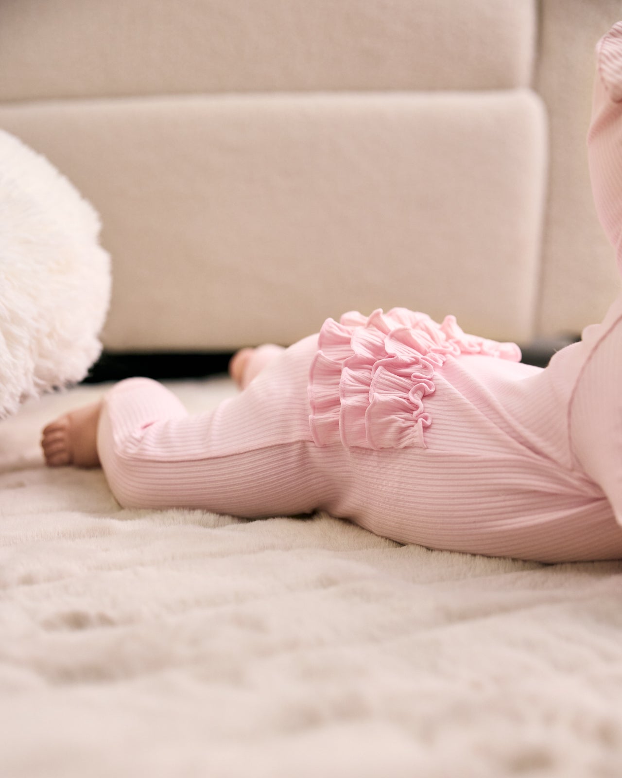 Baby laying on her tummy wearing the Prima Pink Ribbed Ruffle Zippy