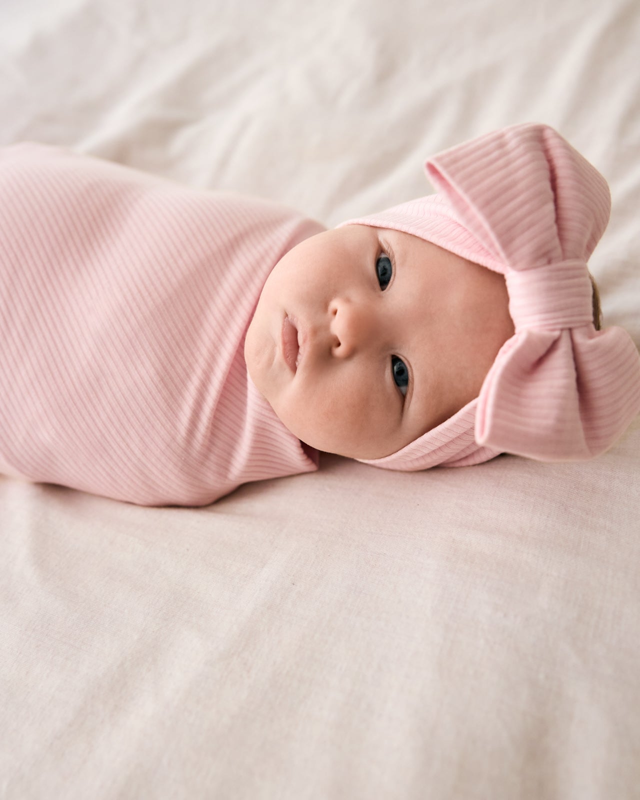 Close up of baby wearing the Prima Pink Ribbed Swaddle & Luxe Bow Headband Set