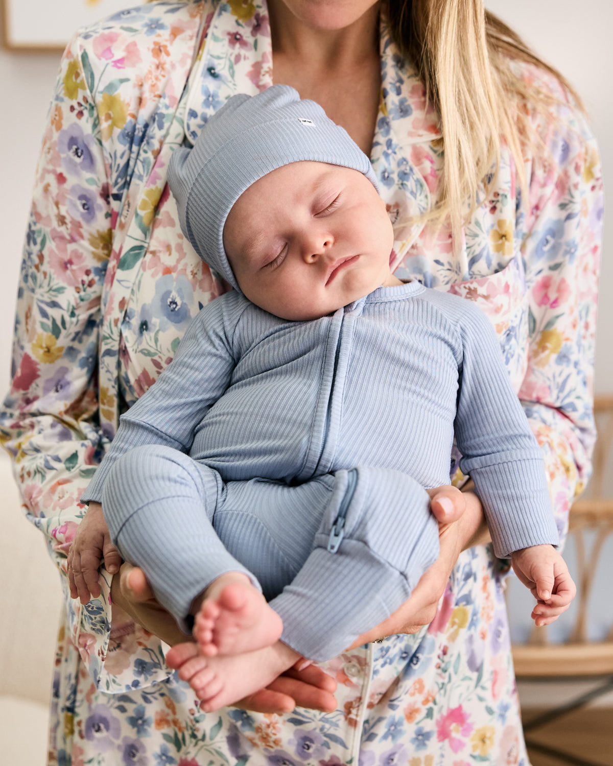 Sleeping baby wearing the Light Fog Ribbed Zippy and a matching blue baby hat