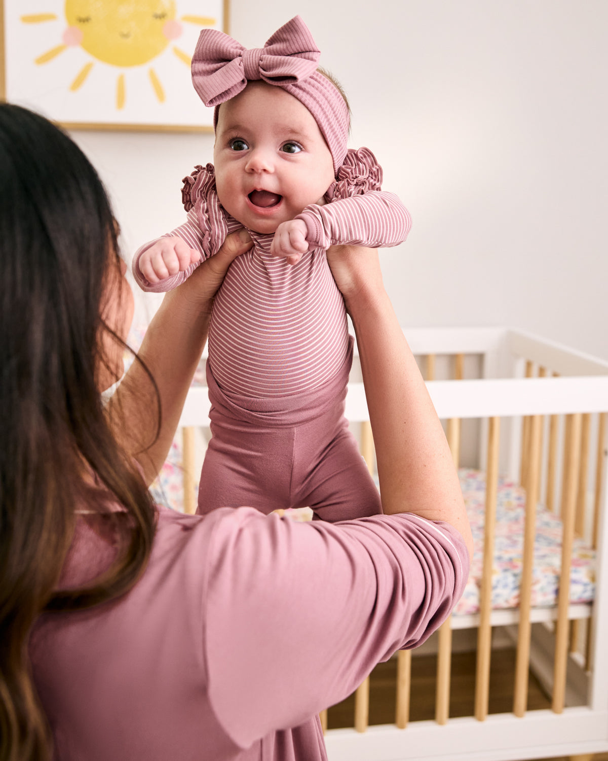 Mom holding baby wearing Rosewood newborn clothing