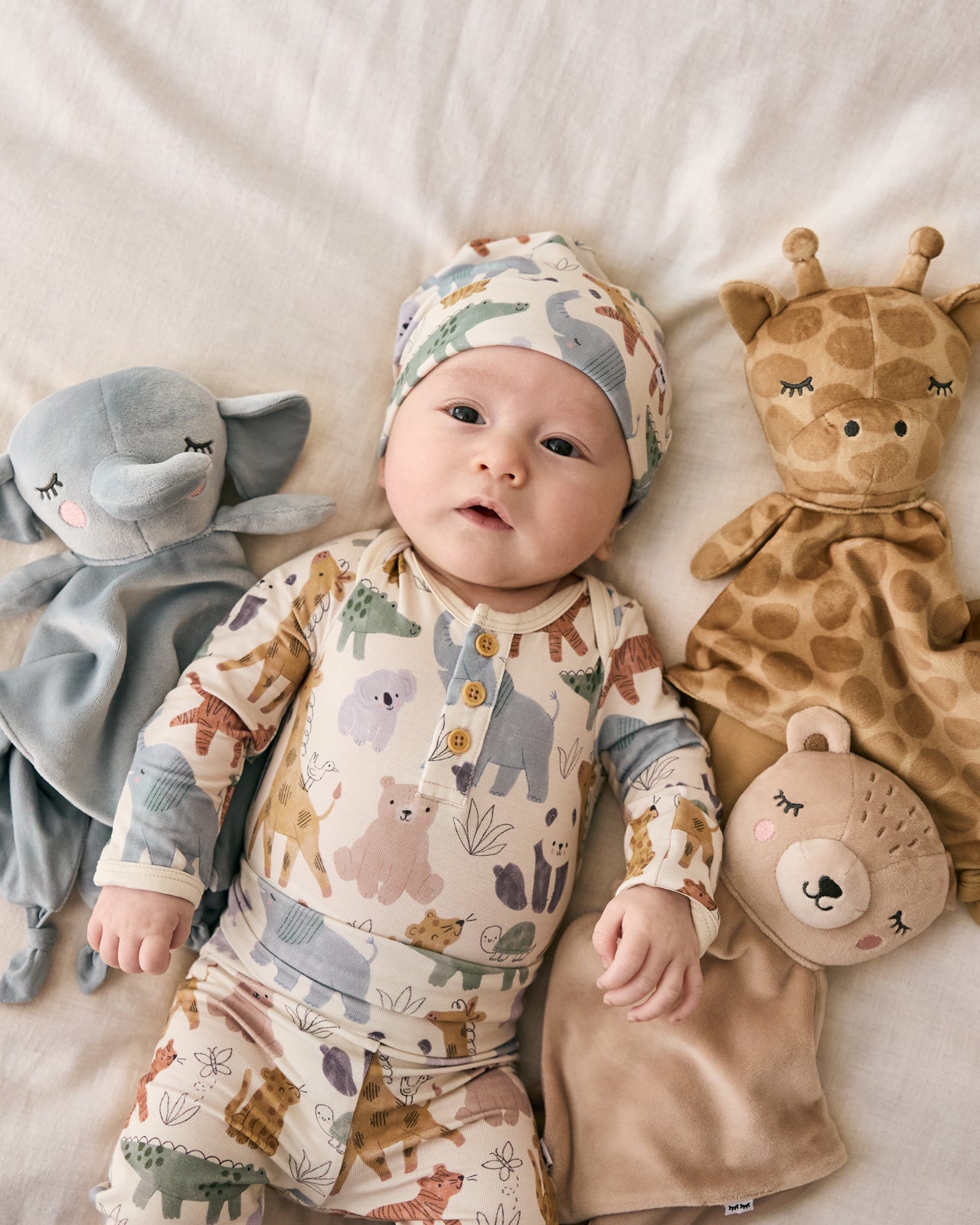 Aerial view of baby laying with three safari themed loveys