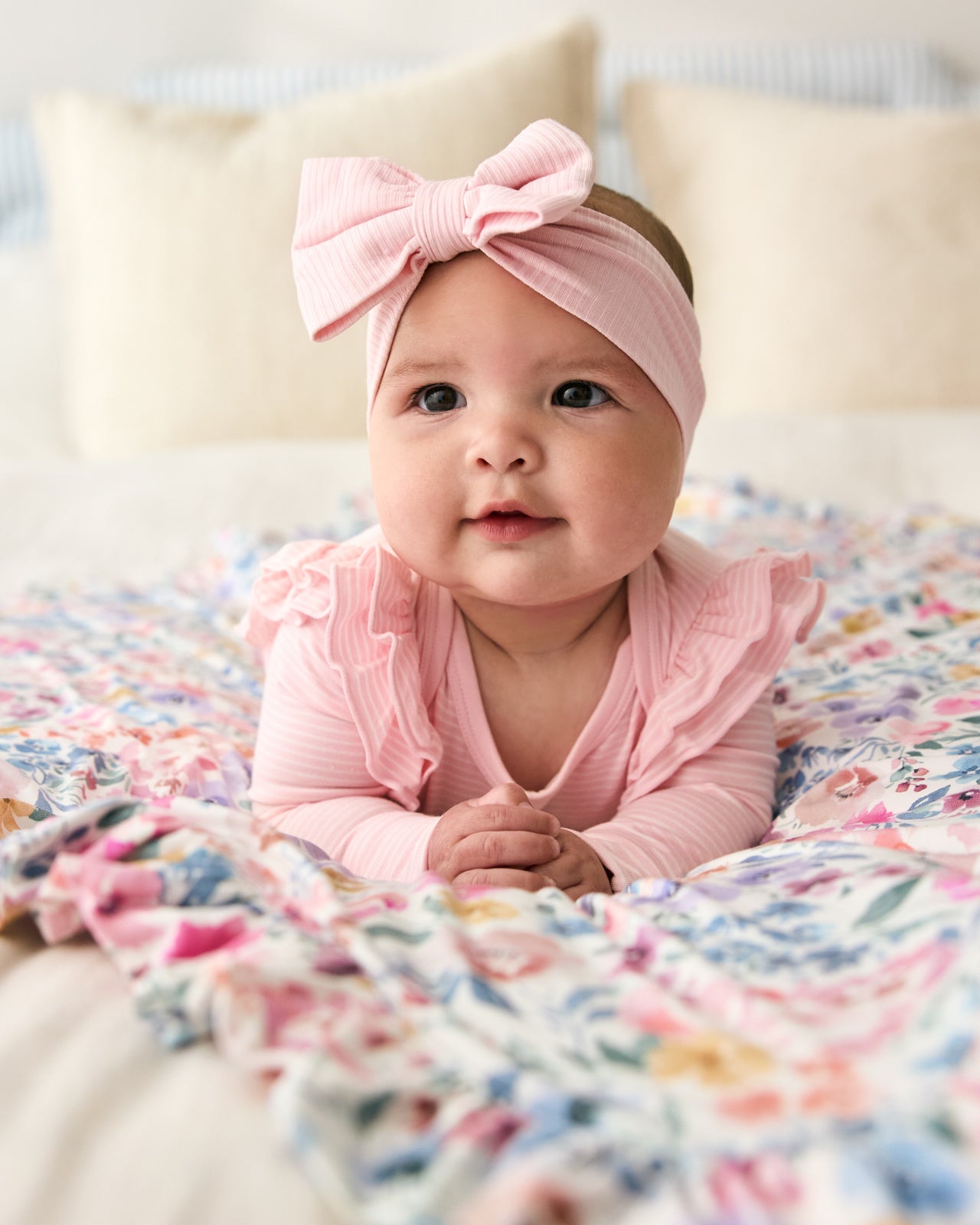 Baby laying on a floral blanket wearing the Prima Pink Ribbed Luxe Bow Headband