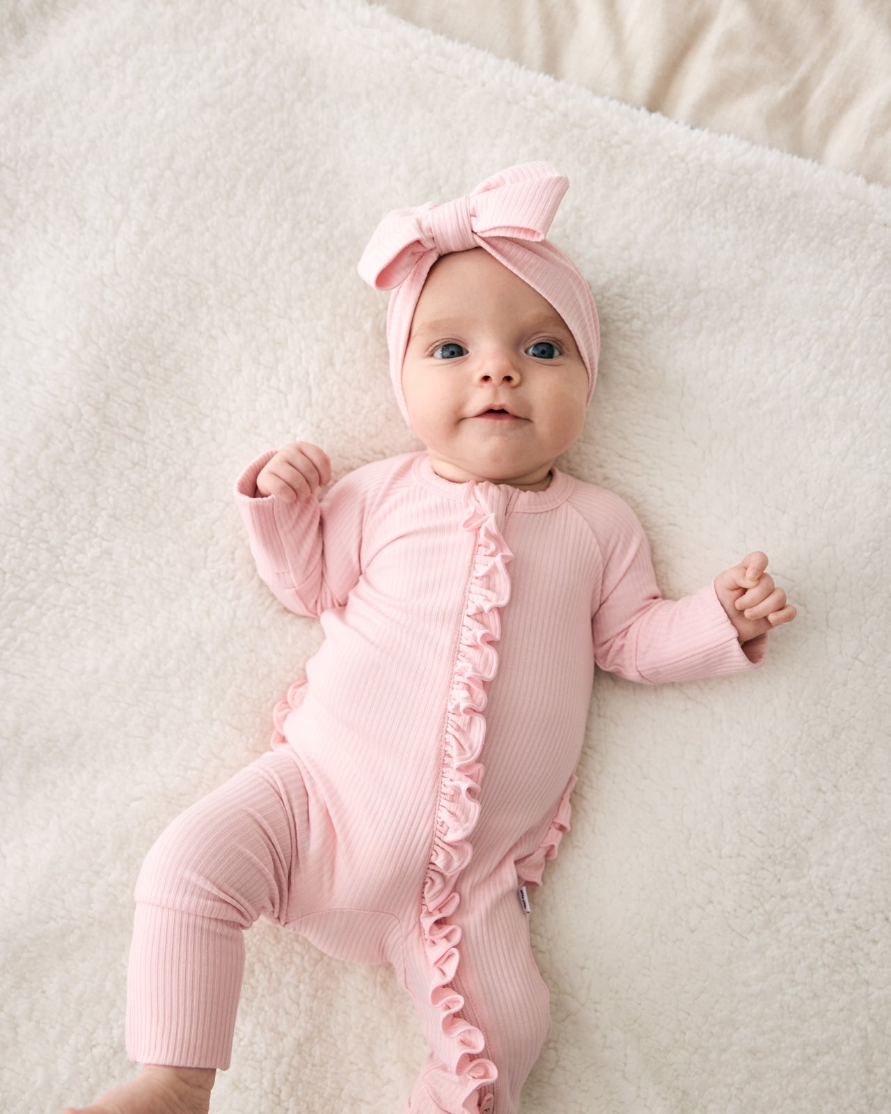 Aerial view of newborn wearing the Prima Pink Ribbed Ruffle Zippy
