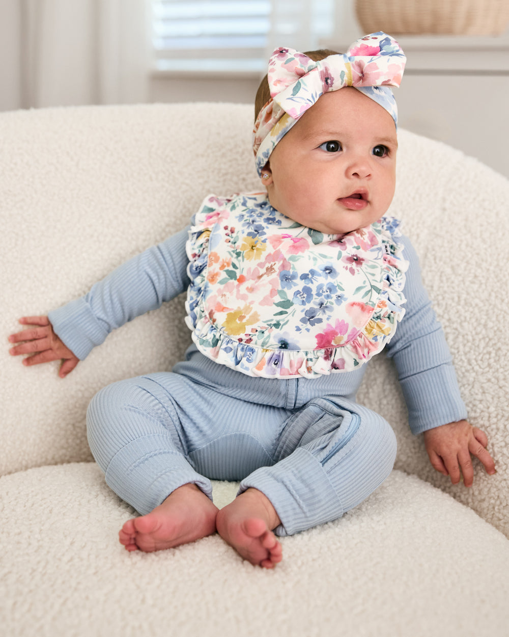 Baby wearing the Tiny Blooms Ruffle Bib with a matching luxe bow headband
