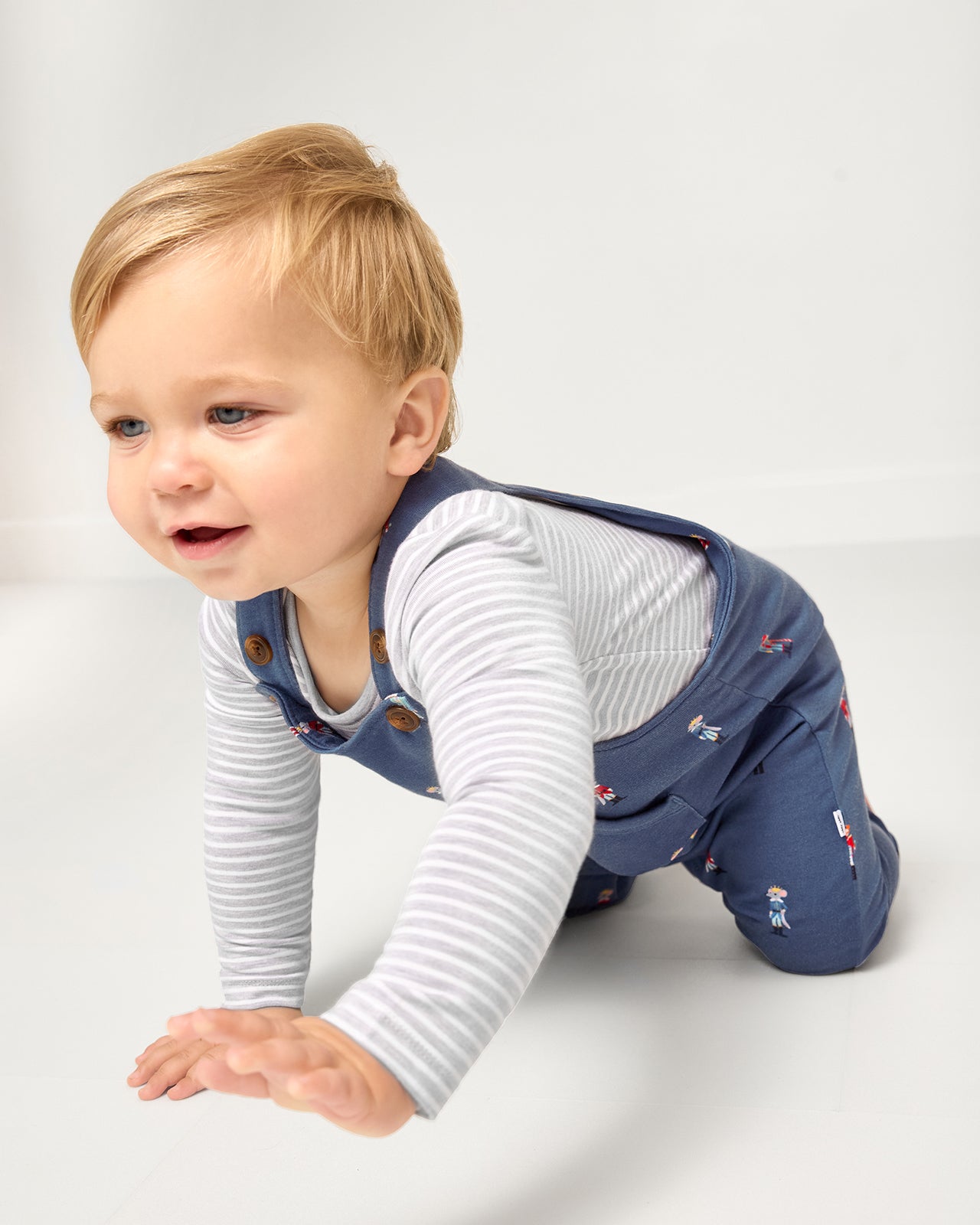 Crawling baby wearing the Light Heather Gray Stripe Bodysuit under the Nutcracker March overalls
