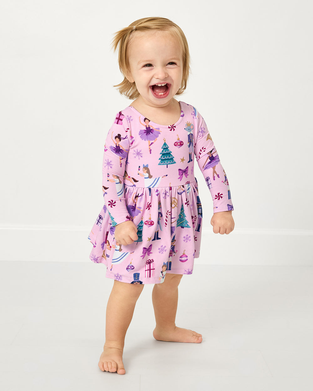 Standing toddler wearing the Nutcracker Ballet Bow Back Skater Dress with Bodysuit
