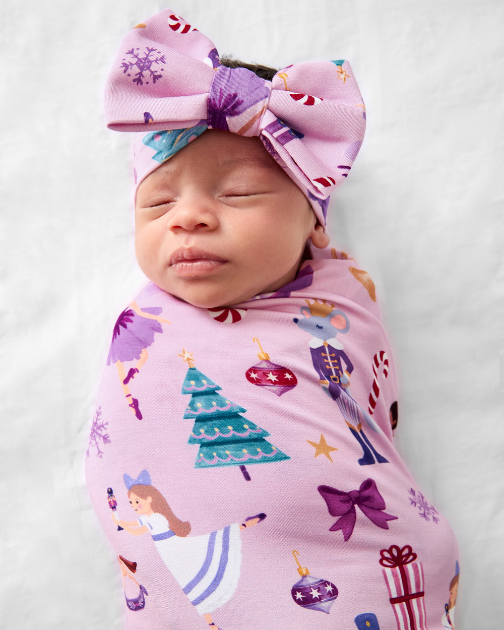 Close up of baby wearing the Nutcracker Ballet Swaddle & Luxe Bow Headband Set