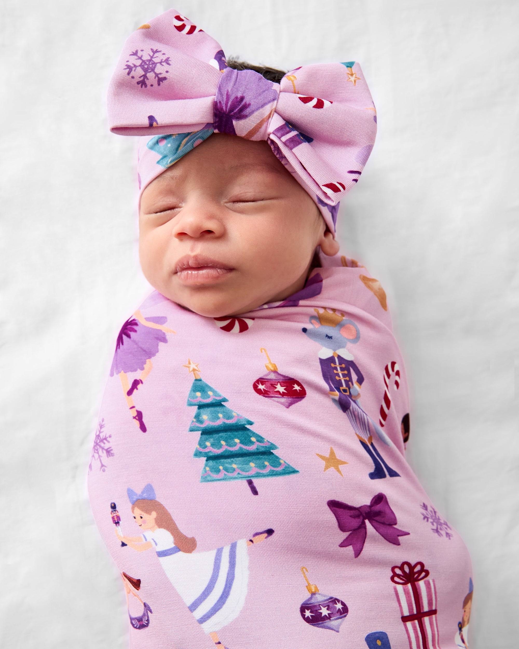 Close up of baby wearing the Nutcracker Ballet Swaddle & Luxe Bow Headband Set