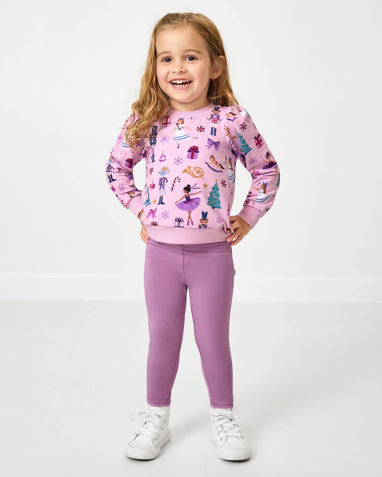 Girl wearing the Nutcracker Ballet Puff Sleeve Crewneck with purple leggings