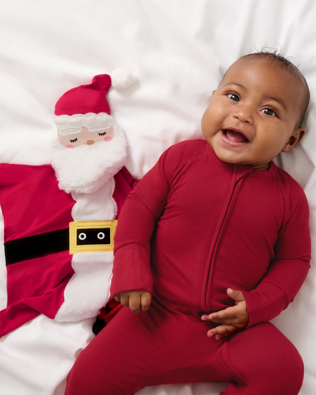 Newborn laying with the Nick the Santa Sleepyhead Lovey wearing a matching red footie PJ