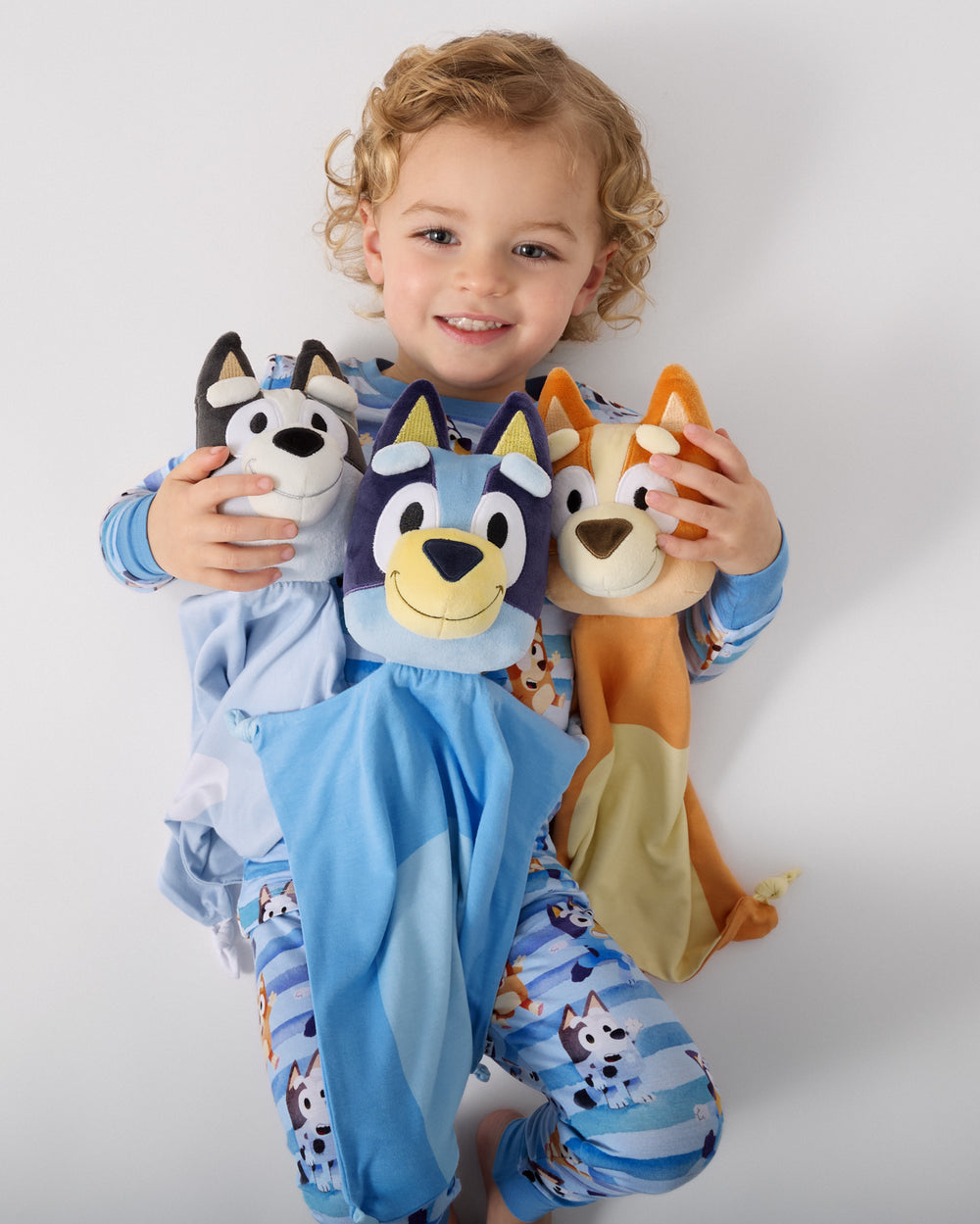 Child laying with the Bluey, Bingo and Muffin Lovies