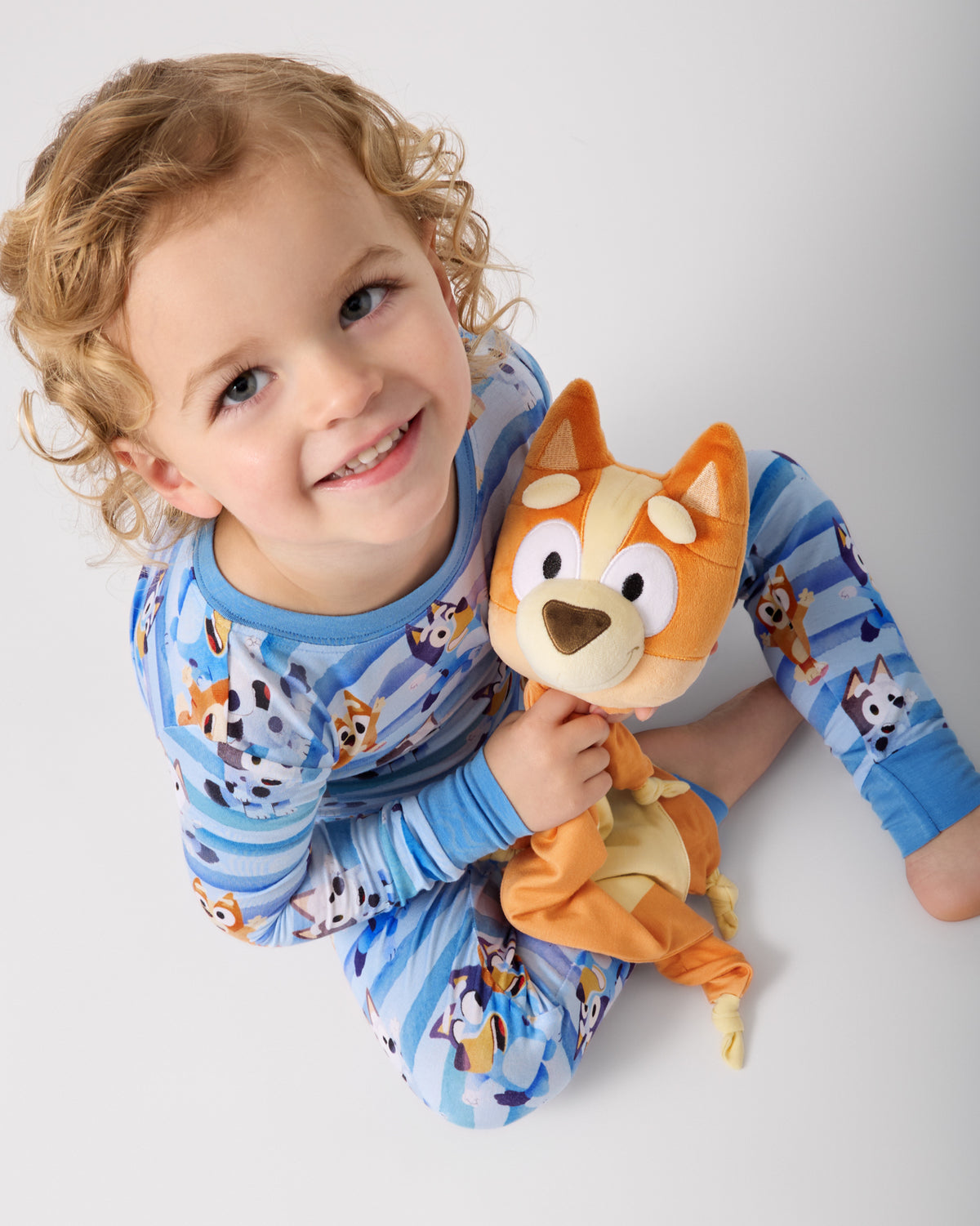 Child holding the Bingo Lovey wearing matching Bluey kids pajamas