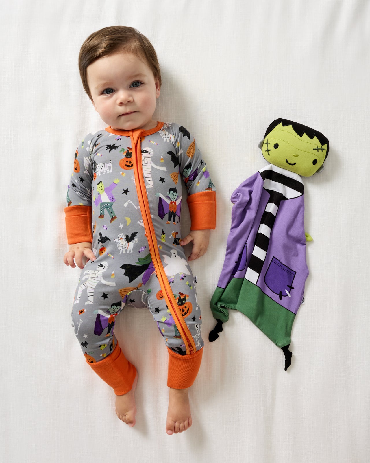 Aerial view of baby laying with the Frankenstein Sleepyhead Lovey wearing halloween bamboo pajamas