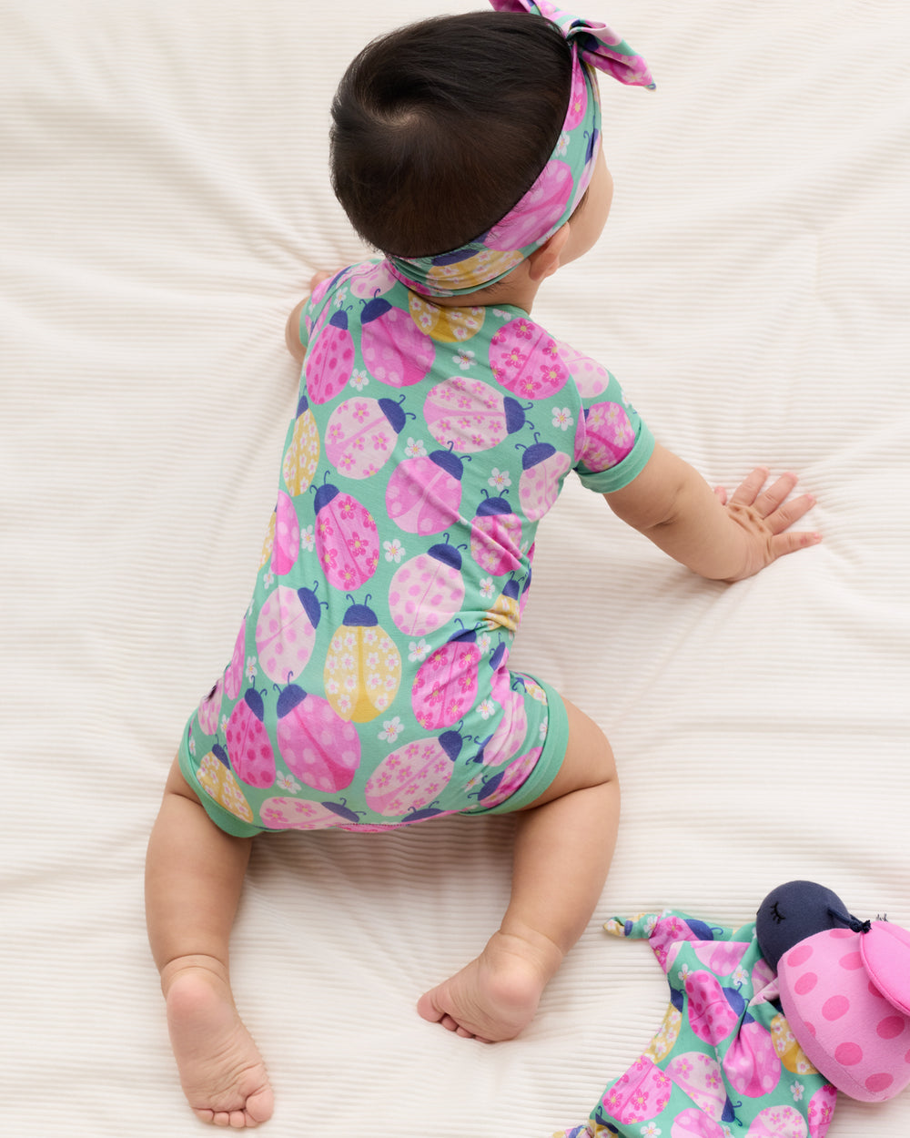 Crawling baby wearing the Ladybug Meadow Shorty Zippy and Luxe Bow Headband