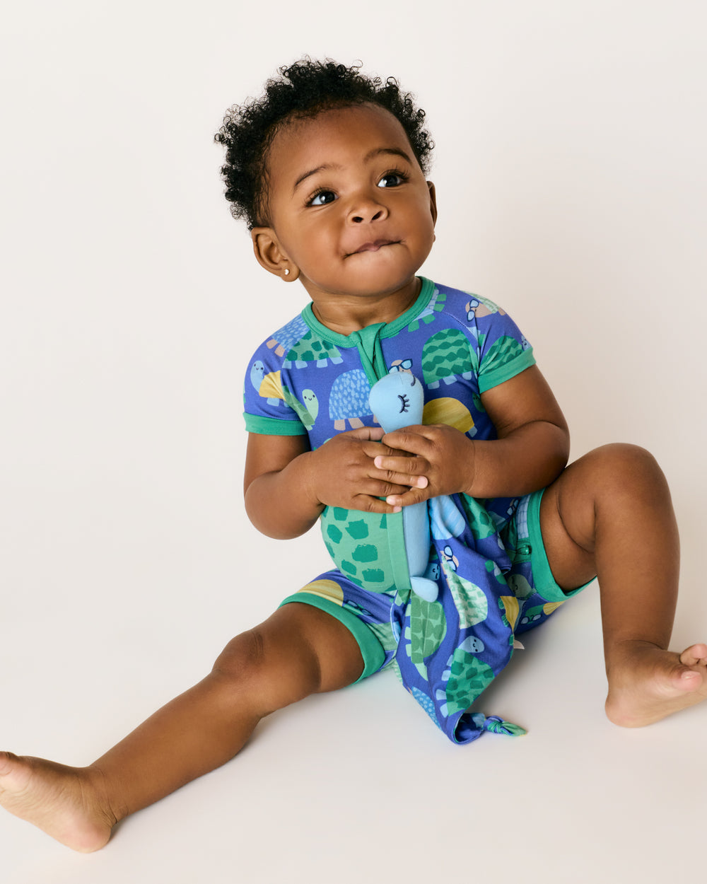 Baby holding the Ty the Turtle Sleepyhead Lovey wearing matching jammies