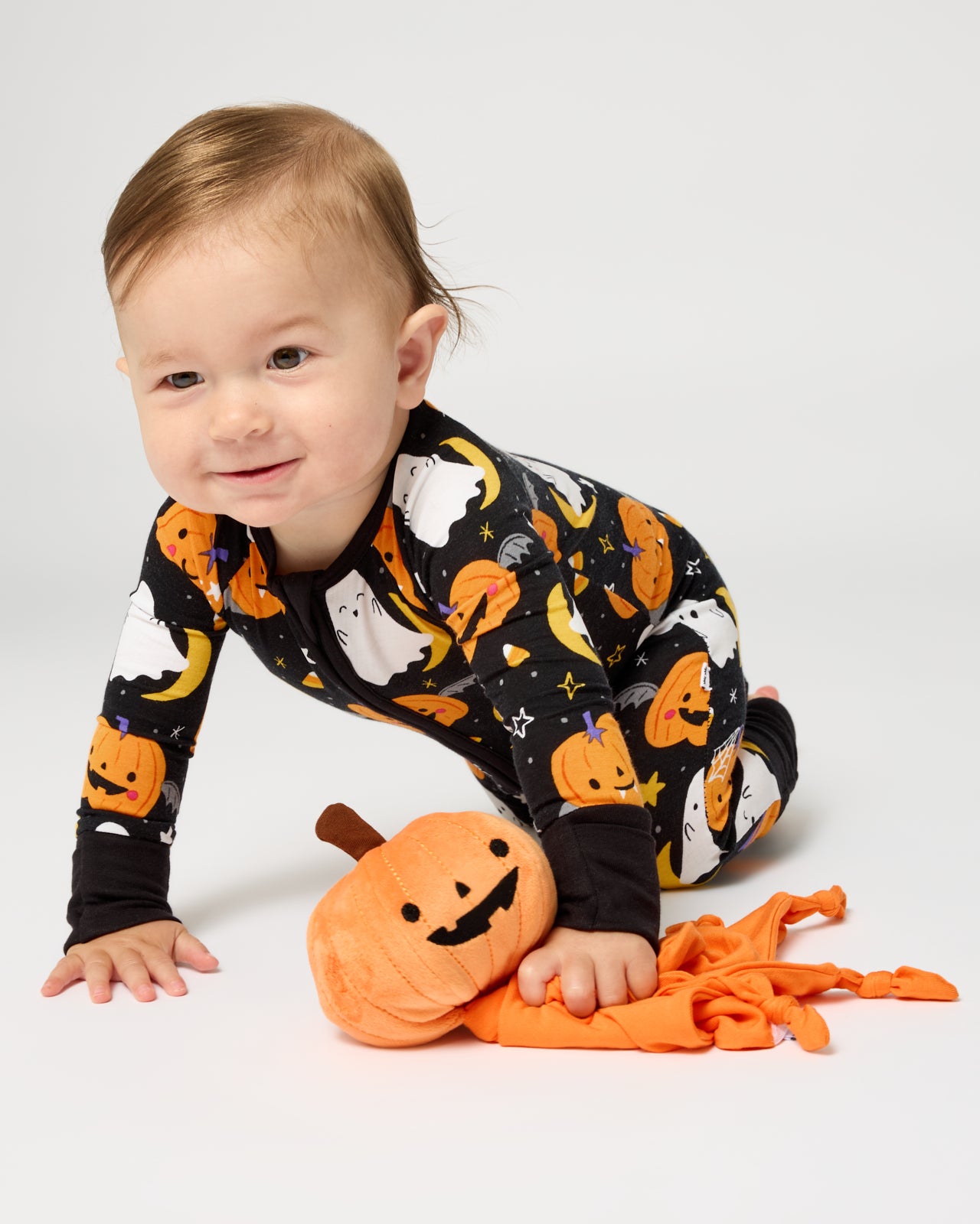 Crawling baby holding the Pumpkin Sleepyhead Lovey