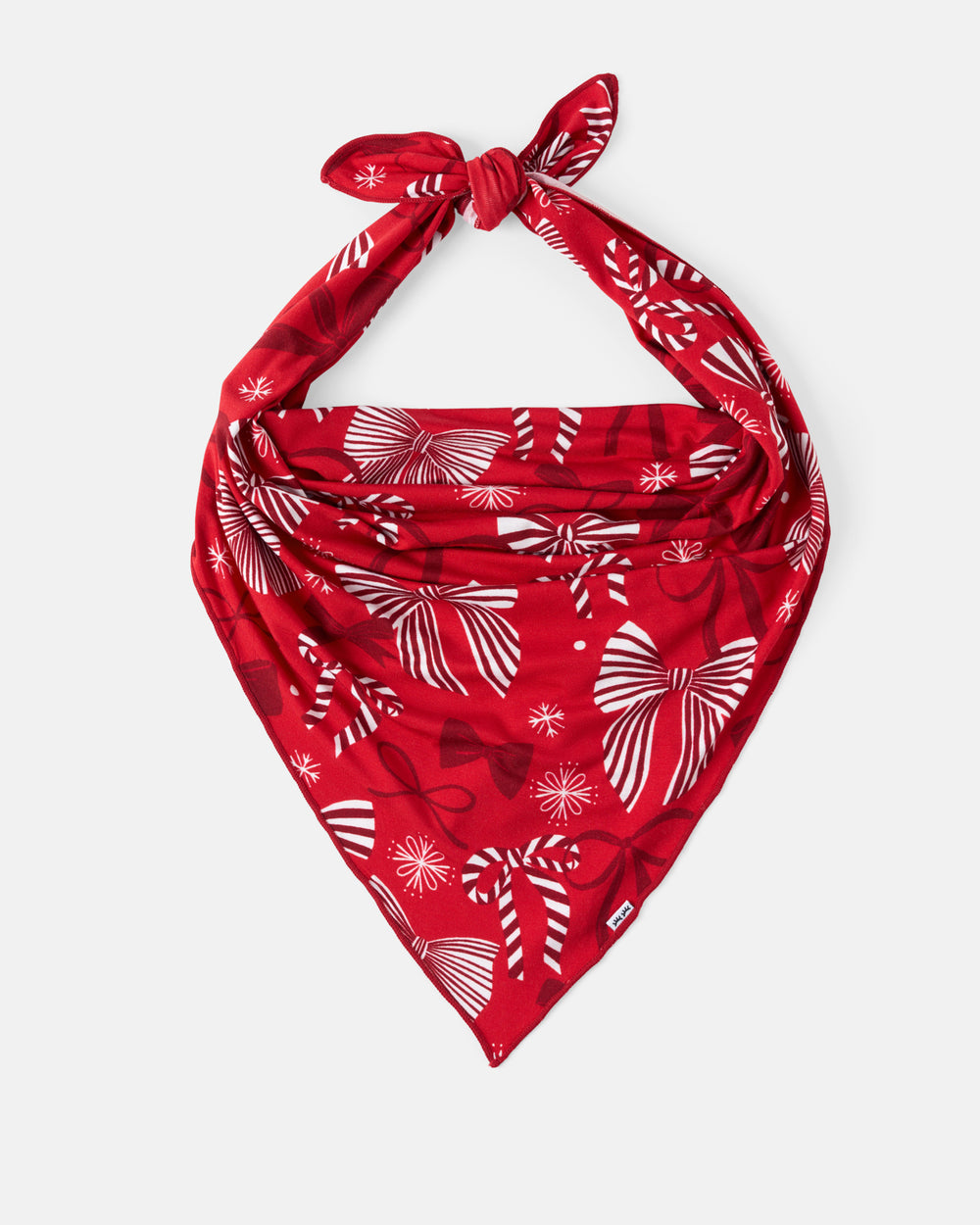 A red bandana with a white holiday-themed print of bows and snowflakes, tied in a knot at the top and displayed against a light gray background.