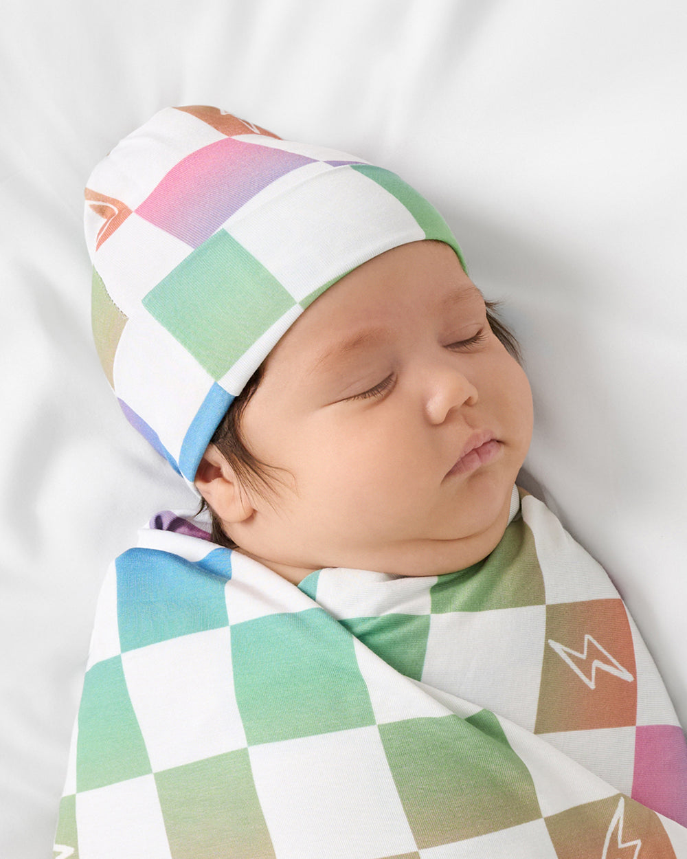 Close up of baby wrapped in the Ombre Cheery Checks Swaddle & Hat Set
