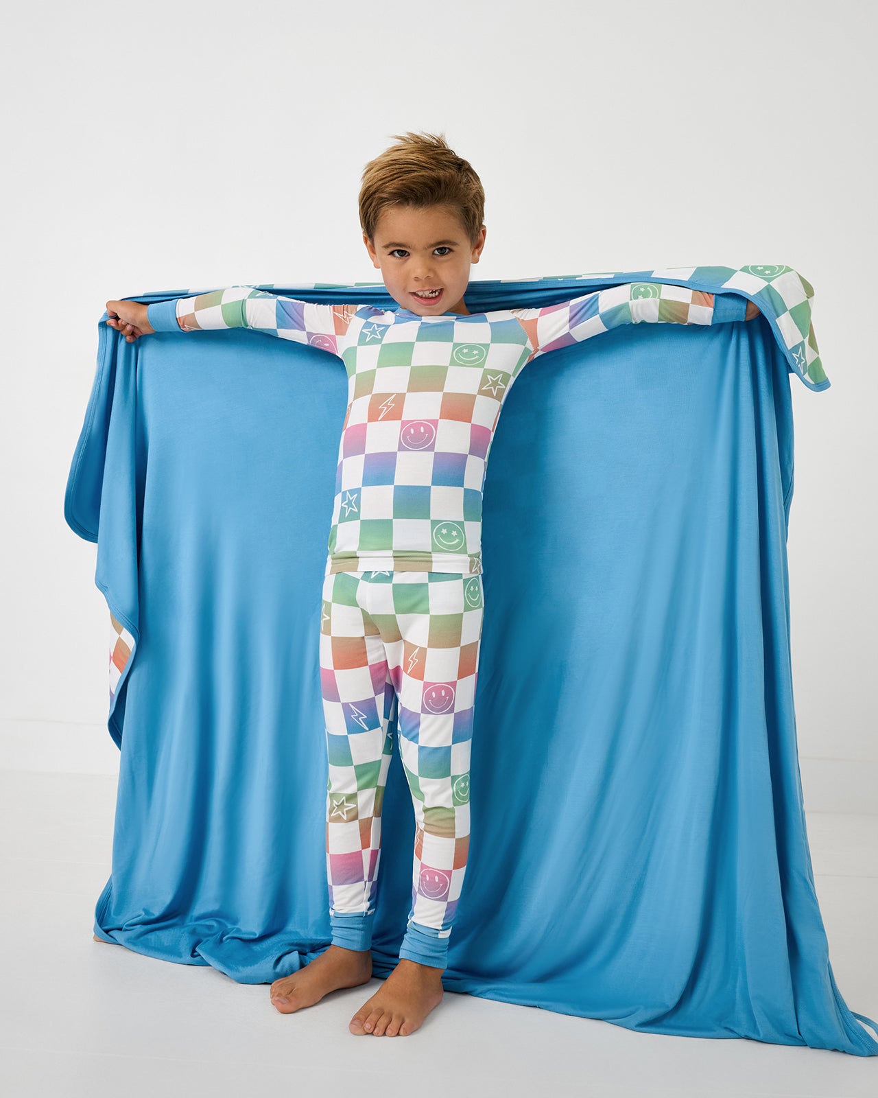 Boy holding up the Ombre Cheery Checks Large Cloud Blanket® showing the solid blue side
