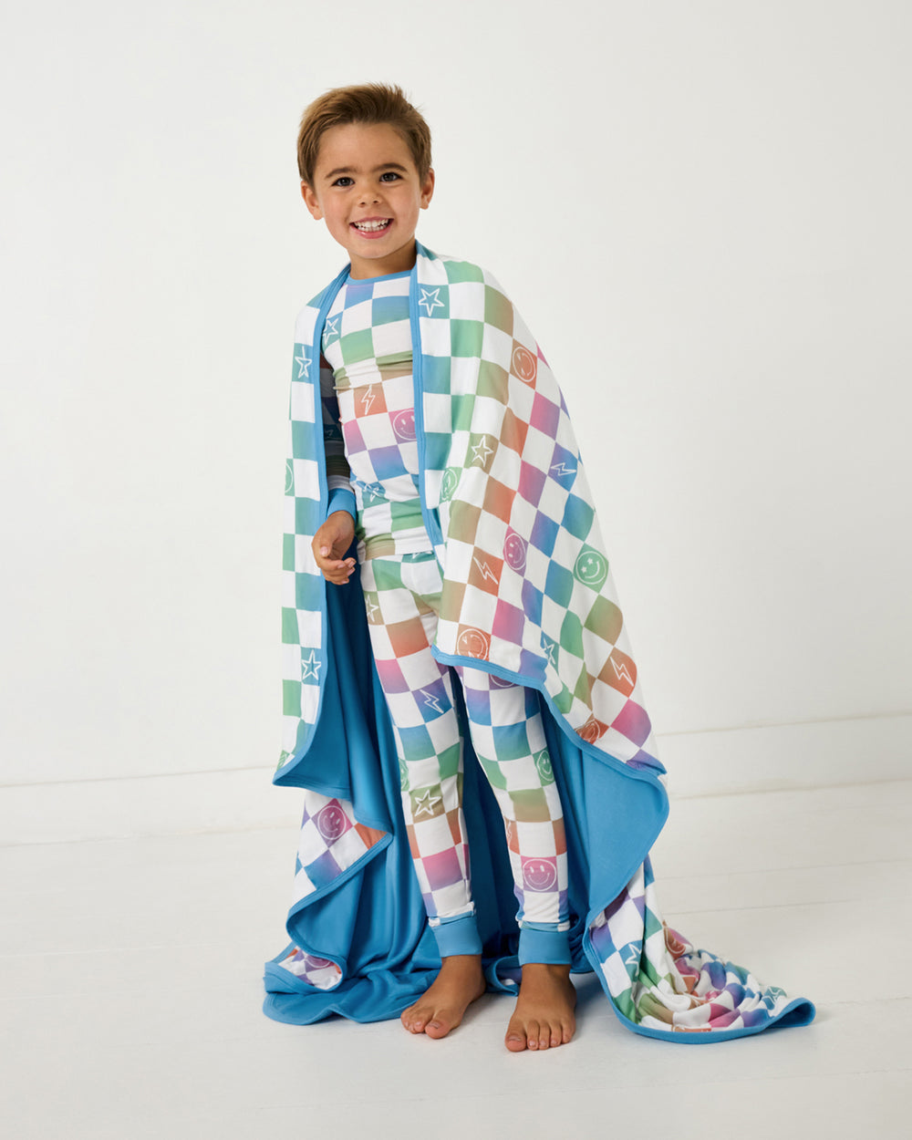 Standing boy wrapped in the Ombre Cheery Checks Large Cloud Blanket®