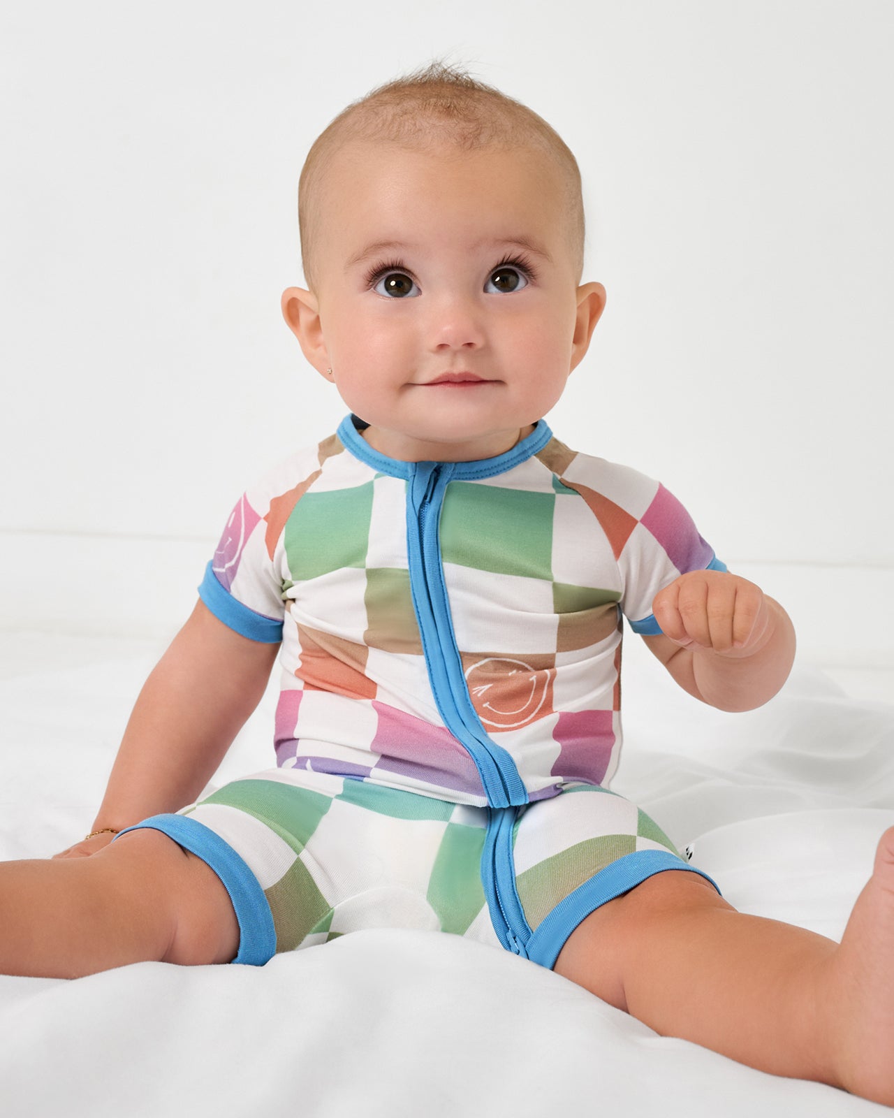 Sitting baby wearing the Ombre Cheery Checks Shorty Zippy