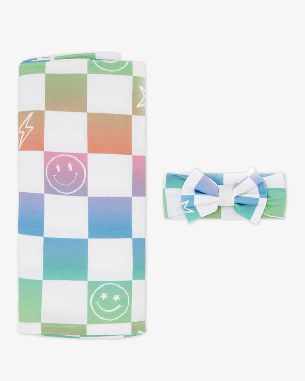 Flat lay of the Ombre Cheery Checks Swaddle & Luxe Bow Headband Set