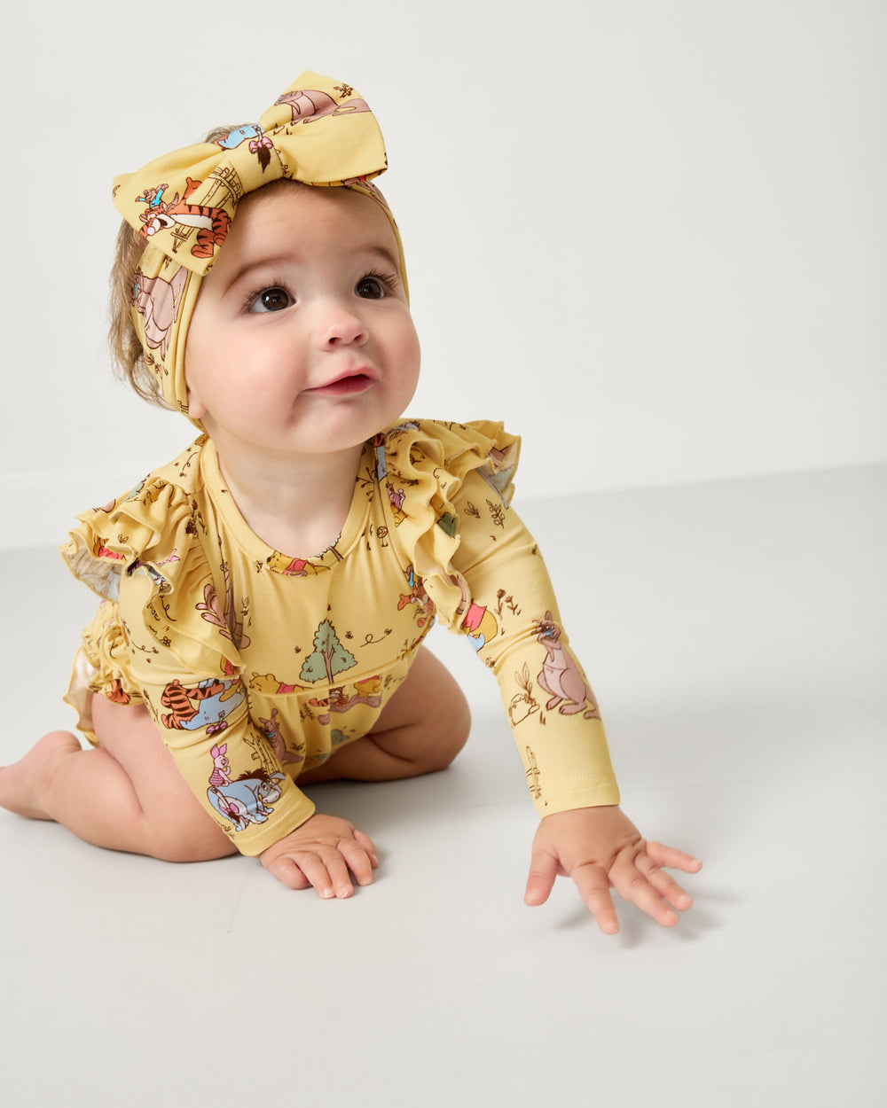 Crawling baby wearing the Disney Playtime With Pooh Luxe Bow Headband