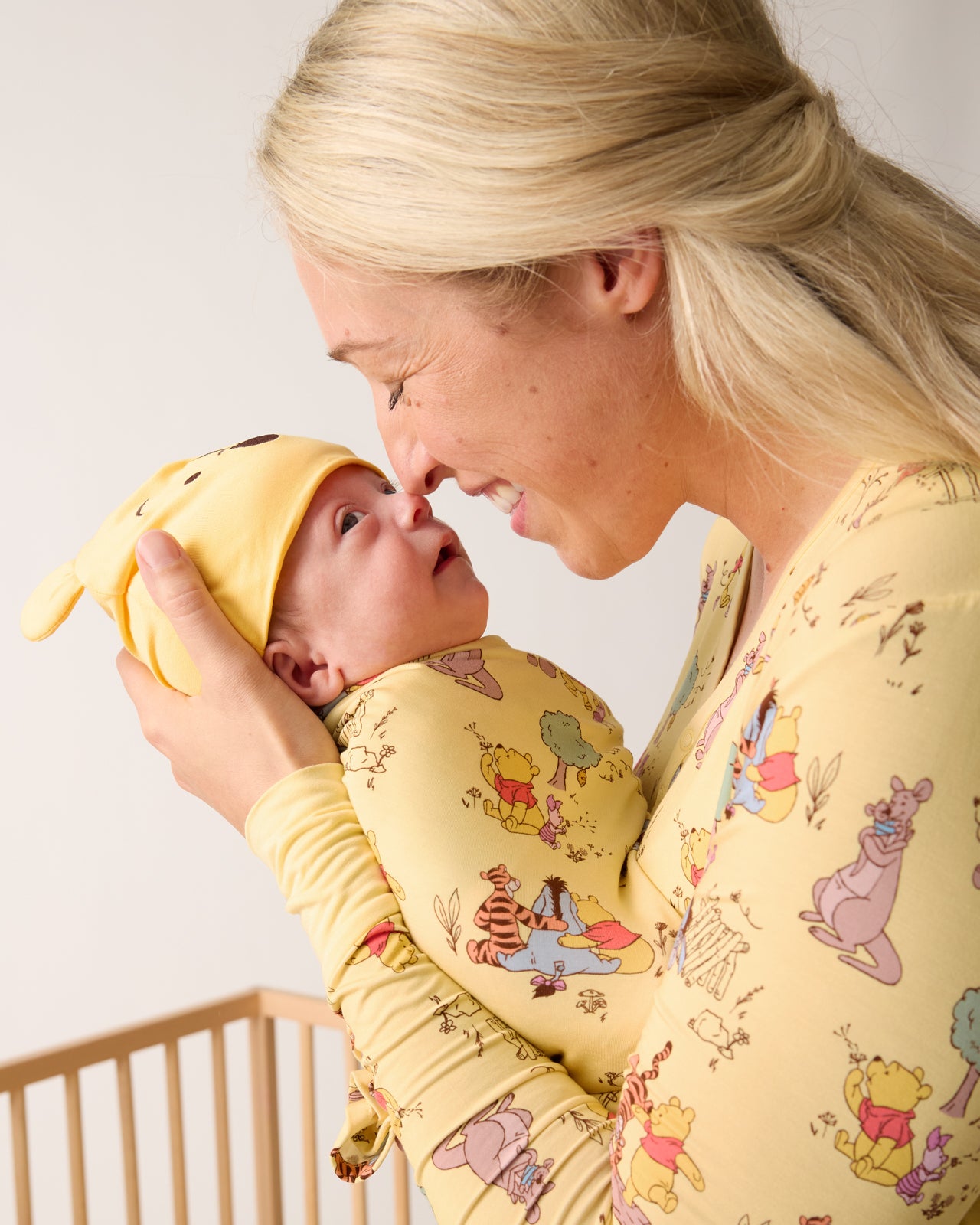 Mother holding baby wearing the Disney Playtime With Pooh Swaddle & Hat Set