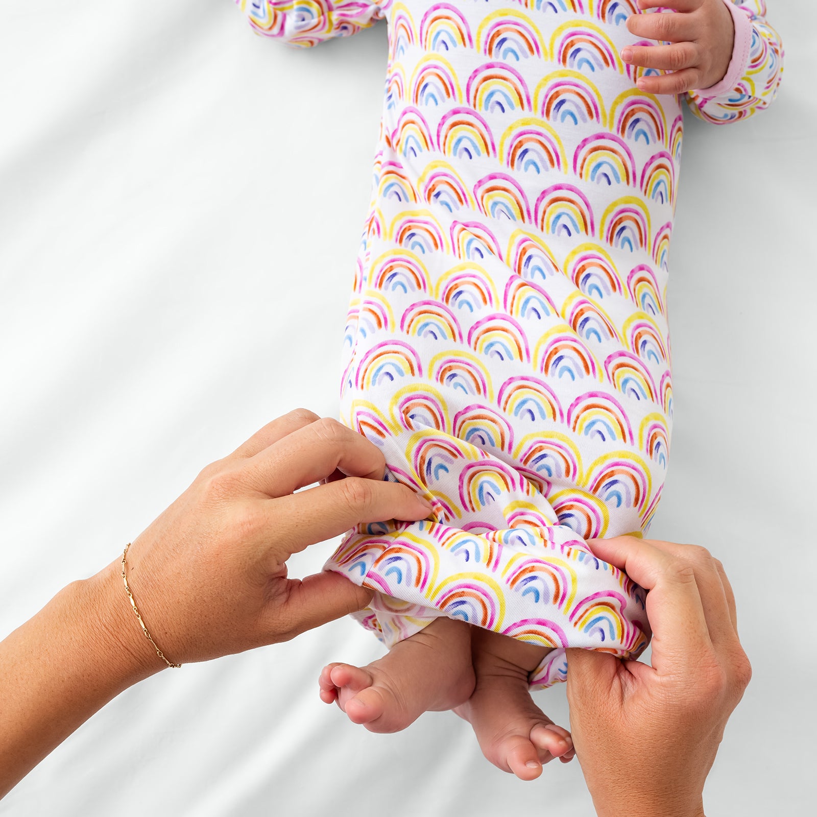Adult demonstrating the envelope sweep on the Pastel Rainbows infant gown