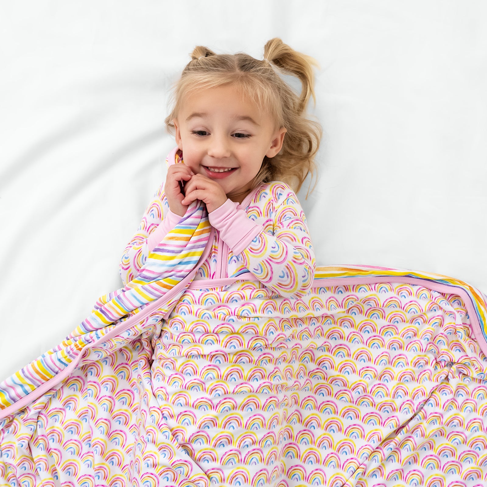 Laying child wrapped in the Pastel Rainbows & Sunrise Stripes Large Cloud Blanket®