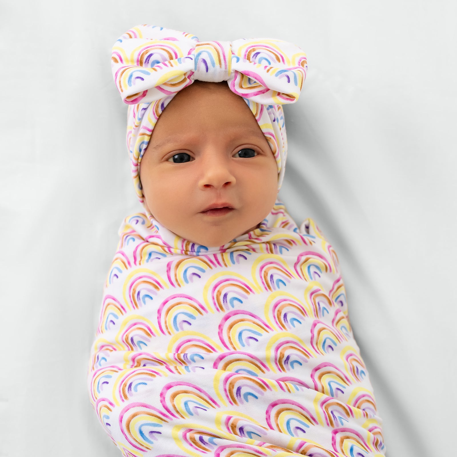 Close up of child in the Pastel Rainbows Swaddle & Luxe Bow Headband Set