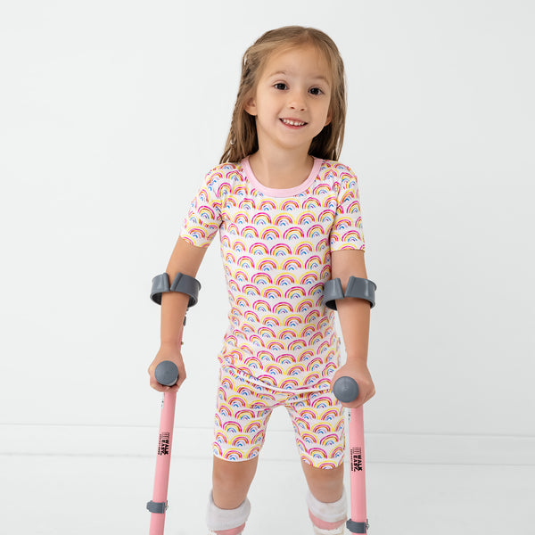 Girl wearing the Pastel Rainbows Two-Piece Short Sleeve & Shorts Pajama Set