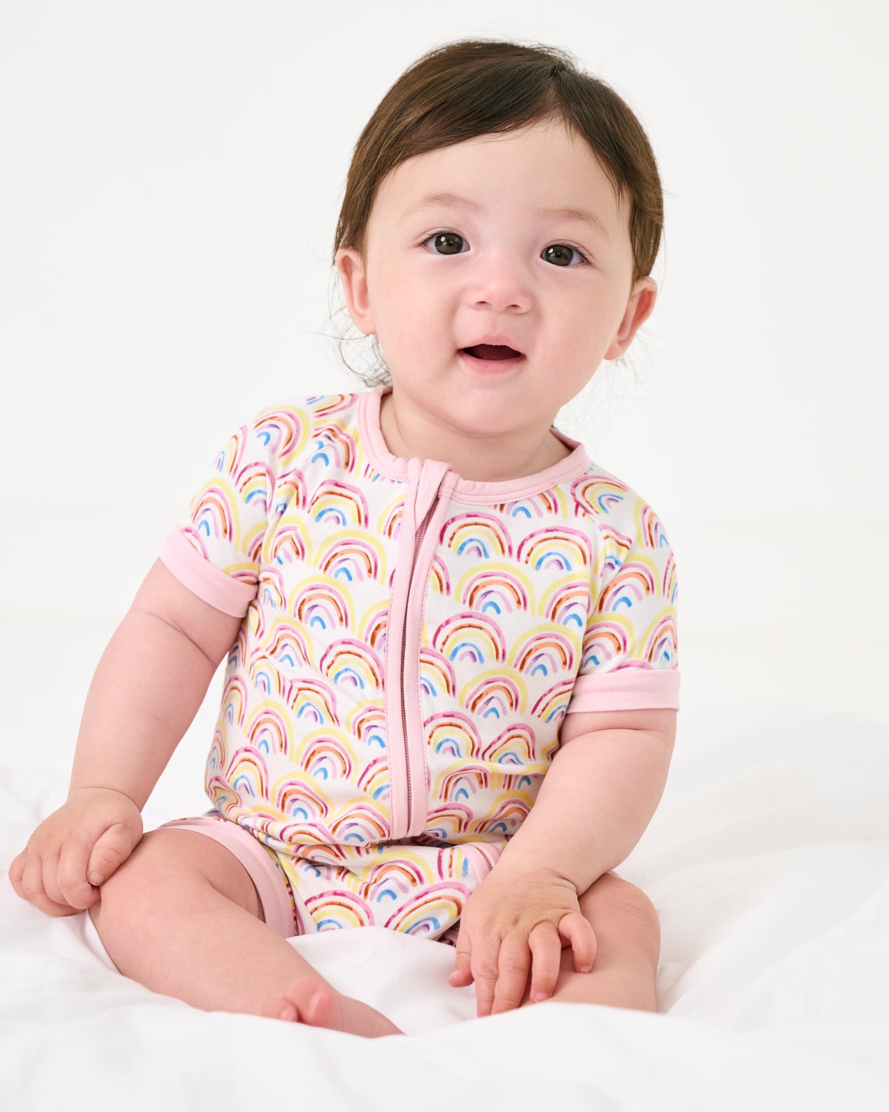 Sitting baby wearing the Pastel Rainbows Shorty Zippy