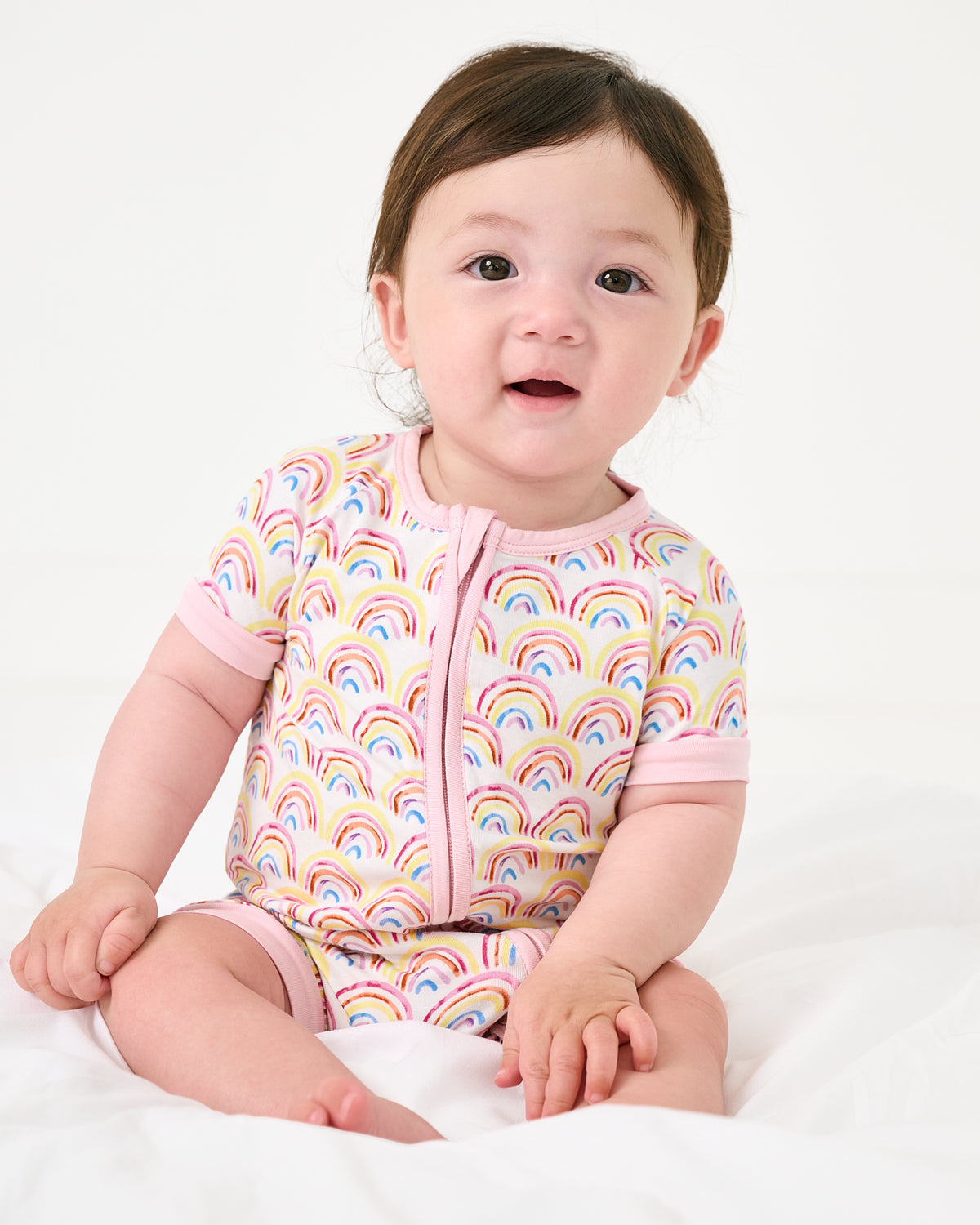 Sitting baby wearing the Pastel Rainbows Shorty Zippy