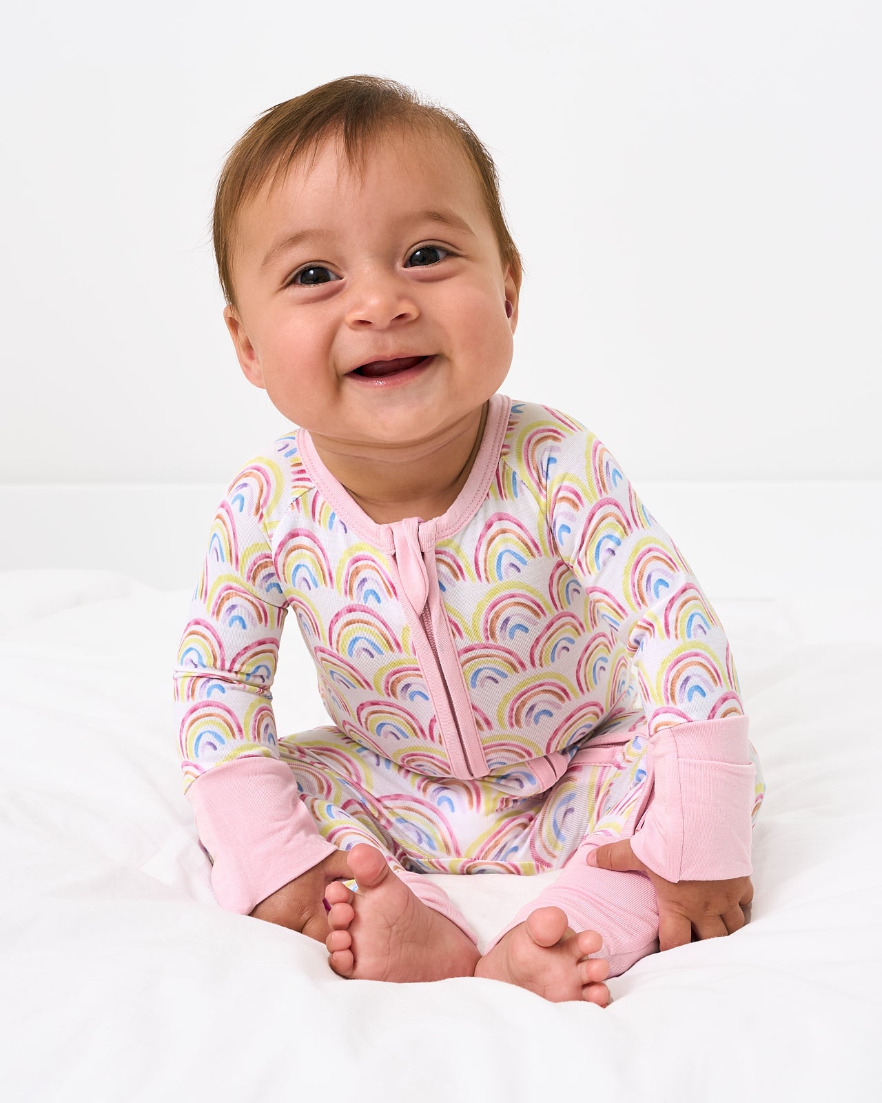 Sitting baby wearing the Pastel Rainbows Zippy