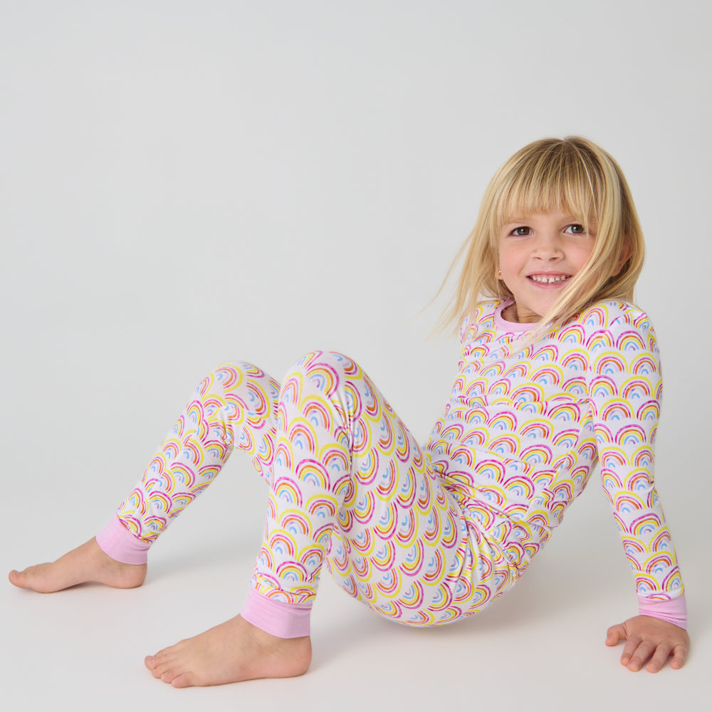 Sitting child wearing the Pastel Rainbows Two-Piece Pajama Set