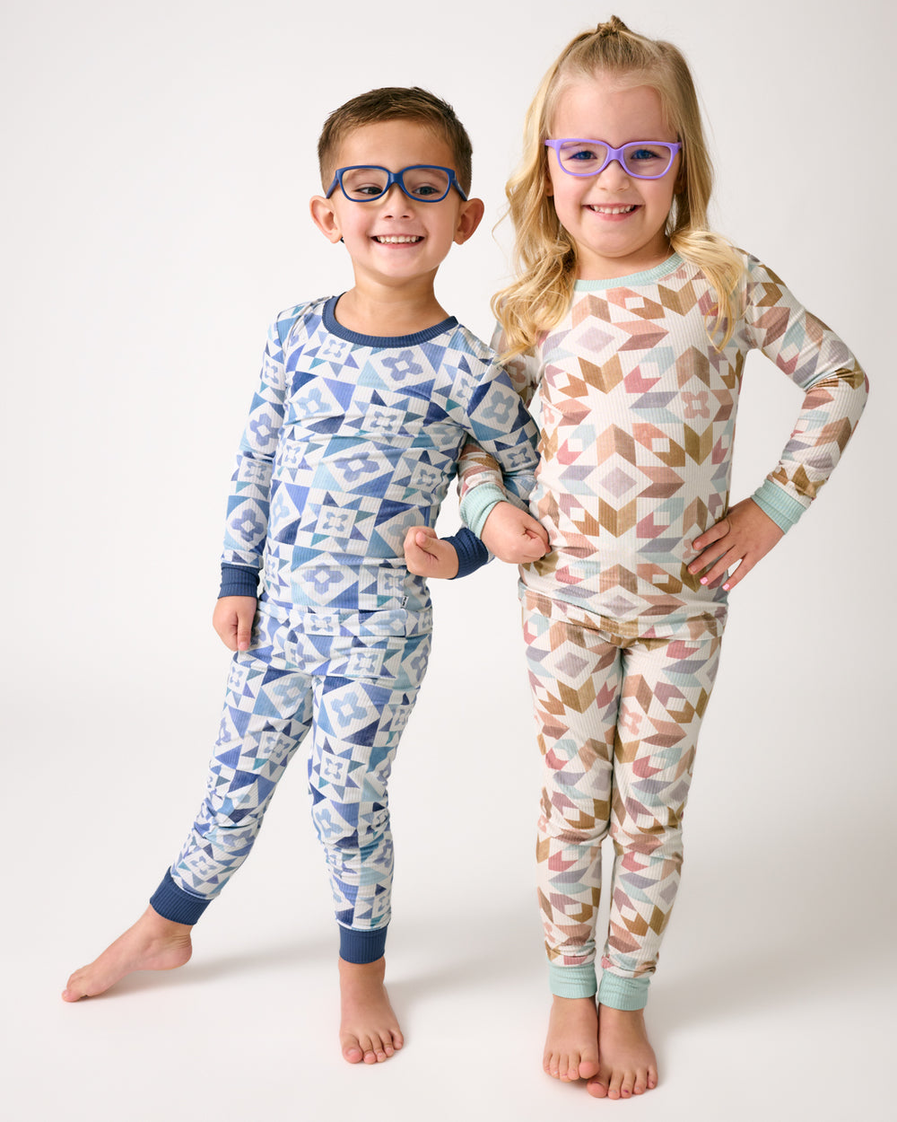 Two children wearing matching Patchwork Indigo and Kaleidoscope Dreams pajamas