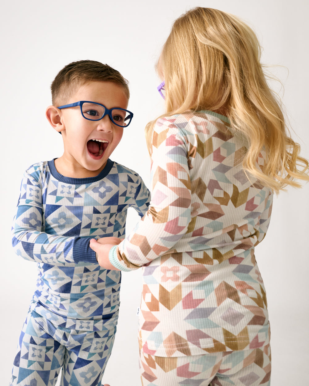 Two dancing children wearing Patchwork Indigo and Kaleidoscope Dreams pajamas