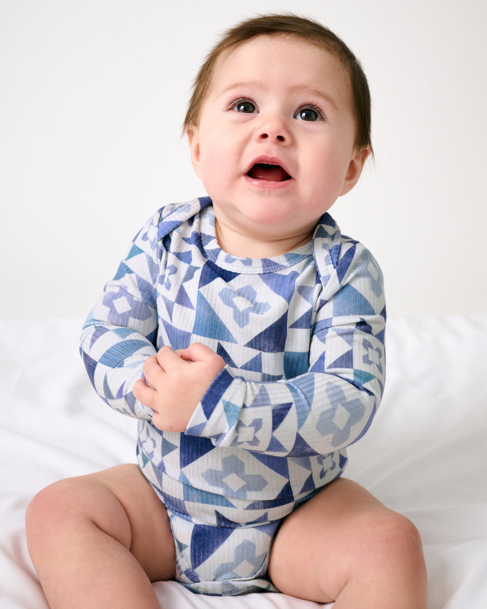 Sitting baby wearing the Patchwork Indigo Ribbed Bodysuit